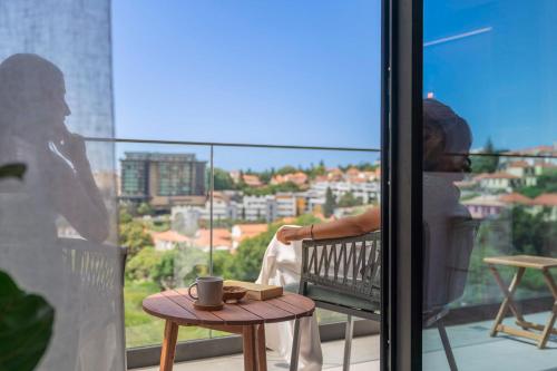 a person sitting on a balcony with a coffee cup on a table at Uptown 13 apartment by An Island Apart in Funchal