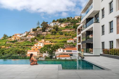 a woman squatting next to a pool in a building at Funchal with pool - Uptown 13 apartment in Funchal