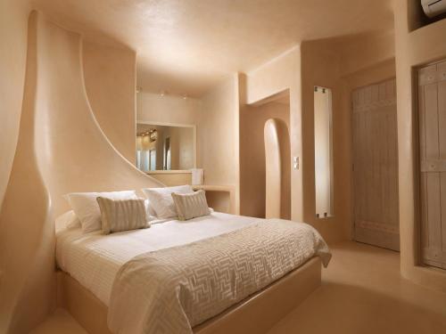 um quarto com uma cama grande com lençóis brancos e almofadas em Dome Santorini Resort & Spa em Imerovigli