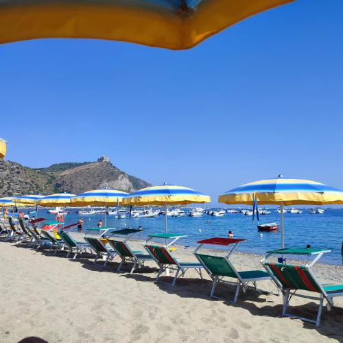 una fila de sillas y sombrillas en una playa en Baia blu falcone, en Falcone