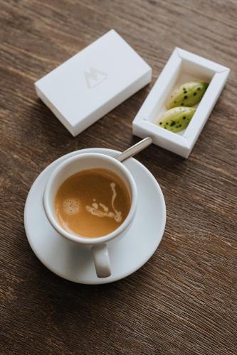 a cup of coffee on a table next to a box of pickles at Hotel Lugano in Knokke-Heist