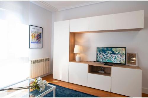 uma sala de estar com armários brancos e uma televisão em Luminoso y Azul em Avilés