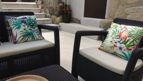 two wicker chairs with pillows on a patio at A CASIÑA DA EIRAVELLA in Hio