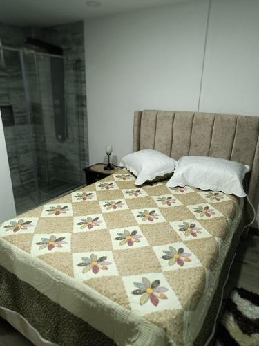 a bed with a quilt with flowers on it at Apartamento en Tunja in Tunja