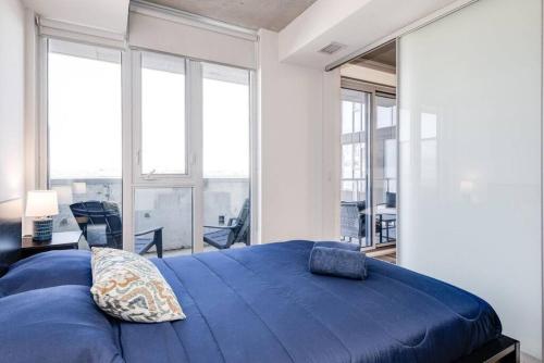 a bedroom with a large blue bed and large windows at South Riverdale Suite with High speed WiFi and Balcony in Toronto