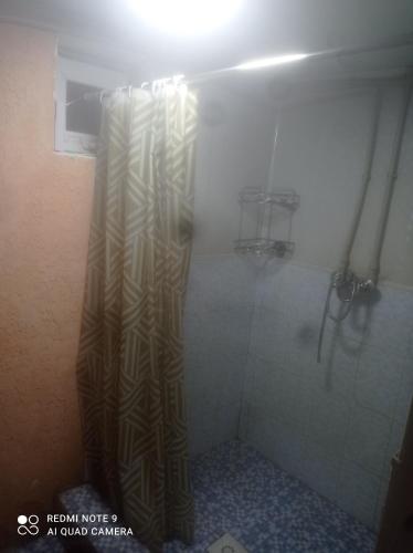 a shower with a shower curtain in a bathroom at Hostel Kanikei in Dzhetyoguz