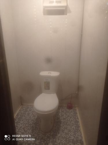 a bathroom with a white toilet in a stall at Hostel Kanikei in Dzhetyoguz