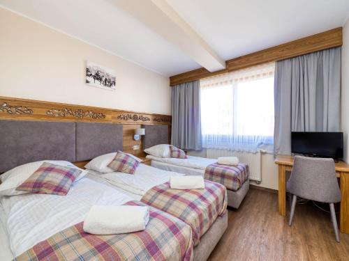 a hotel room with two beds and a flat screen tv at Dom Wypoczynkowy U Chramca in Białka Tatrzanska