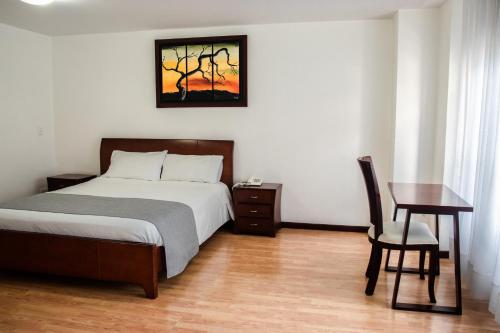 1 dormitorio con cama, mesa y escritorio en Nogal Suite Hotel, en Pasto