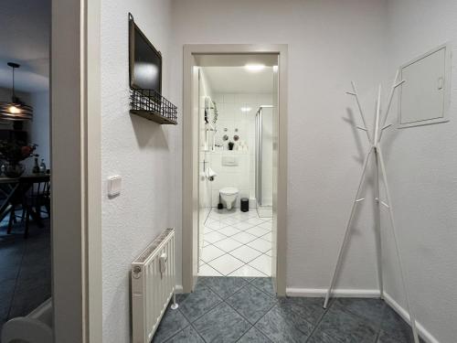 a white hallway with a bathroom with a refrigerator at Pfälzer Weinperle mit Terrasse in Hainfeld