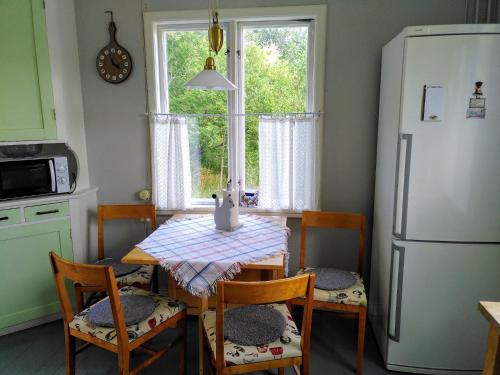y cocina con mesa, sillas y nevera. en Lägenhet naturnära i Henån en Henån