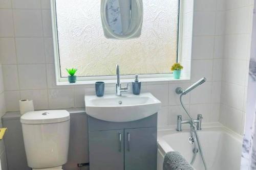 a bathroom with a sink and a toilet and a tub at Lovely 3 Bed with Free parking-Families, Professionals and Contractors Welcome in Luton