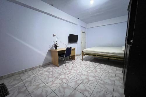 een kamer met een bed en een bureau met een computer bij OYO 92892 Aini Homestay in Ternate