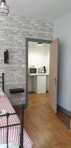 a bedroom with a brick wall and a door to a kitchen at Le moulin de Clauzure - Périgord vert in Saint-Paul-Lizonne