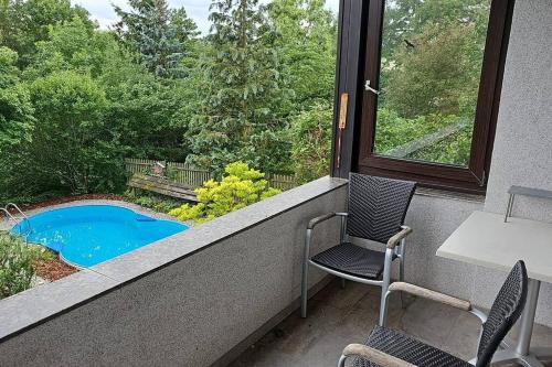 einen Balkon mit 2 Stühlen, einem Tisch und einem Pool in der Unterkunft Cityappartement am Kirschberg in Weimar