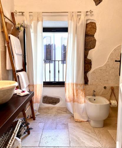 a bathroom with a tub and a toilet and a window at Casa Maria - Charme nel cuore del castello in Castelsardo