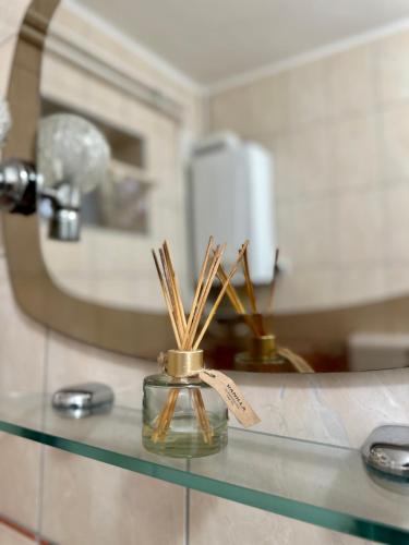 a glass jar with bamboo sticks in it on a counter in a bathroom at Apartman Maja in Srbobran