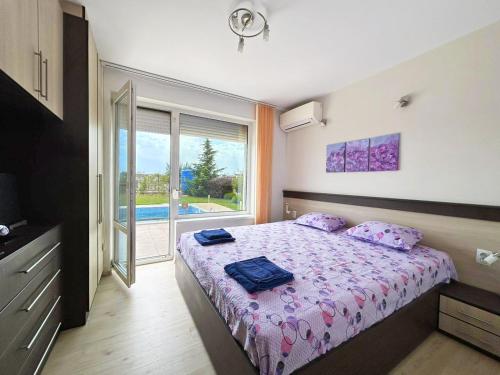 Un dormitorio con una cama con sábanas moradas y una ventana en Golf Villa Ariel, en Kavarna