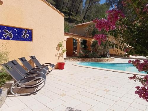 un groupe de chaises assises à côté d'une piscine dans l'établissement LES RESTANQUES - Chambre d'hôtes, à Cuges-les-Pins