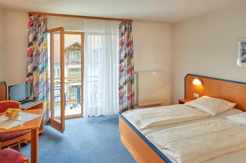 um quarto com uma cama, uma secretária e uma televisão em Trip Inn Aktivhotel & Restaurant Sonnenhof bei Passau em Sonnen