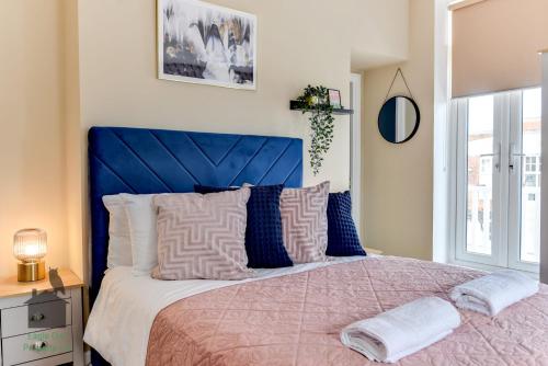 a bed with a blue headboard in a bedroom at Bright studio with turret and parking by Eagle Owl Property in Worthing