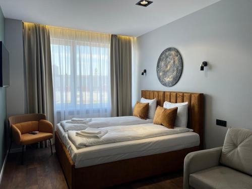 a bedroom with a bed and a chair and a window at Luna Self Check-in Hotel Klaipeda in Klaipėda