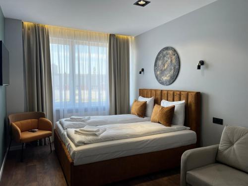 een slaapkamer met een bed, een stoel en een raam bij LUNA Self Check-in Hotel Klaipeda in Klaipėda