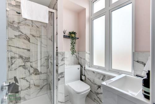 a bathroom with a toilet and a sink and a window at Bright studio with turret and parking by Eagle Owl Property in Worthing