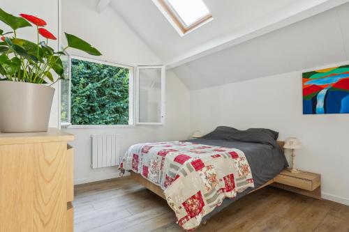 ein Schlafzimmer mit einem Bett und einer Topfpflanze in der Unterkunft Maison charmante avec jardin et parking offert Paris St Cloud in Saint-Cloud