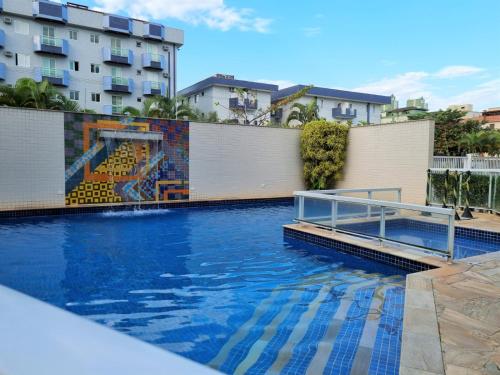 a swimming pool with a mural on the side of a building at Apartamento Avenida Wilson in Ubatuba