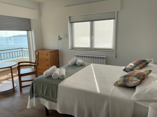 Schlafzimmer mit einem Bett, einem Tisch und einem Fenster in der Unterkunft Villa en Sanxenxo a pie de playa, Barreiros in Sanxenxo