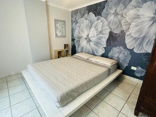 a bedroom with a bed with a flower mural on the wall at La casetta di Bianca - MonferratoHome in Frassinello Monferrato
