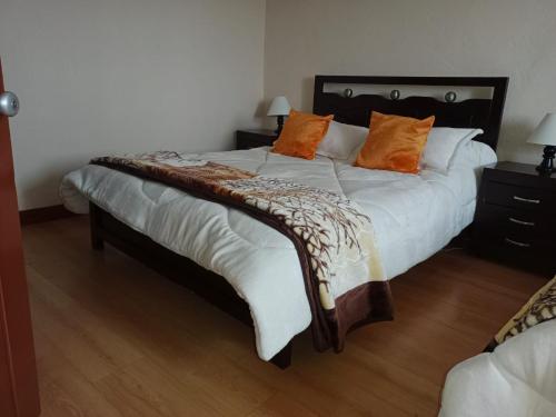 a large bed with orange pillows on top of it at Casa Rural Zaba Lago de Tota in Aquitania