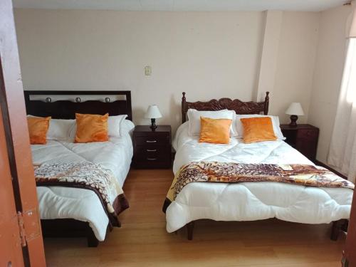 a bedroom with two beds with orange pillows on them at Casa Rural Zaba Lago de Tota in Aquitania