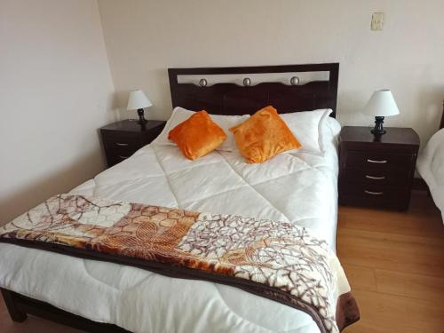 a bedroom with a bed with two orange pillows on it at Casa Rural Zaba Lago de Tota in Aquitania
