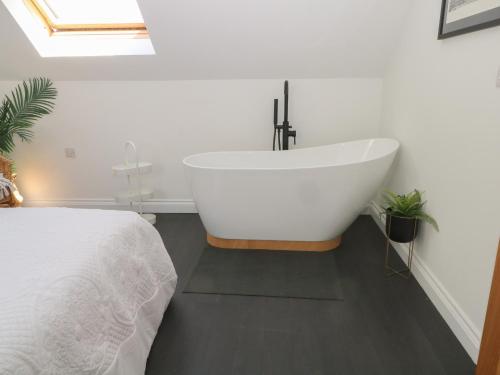 a white bath tub in a bedroom with a bed at Bodlywydd Fawr - Annexe in Ruthin