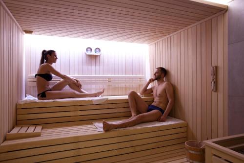 a man and a woman sitting in a sauna at Hotel Le Grotte in Genga