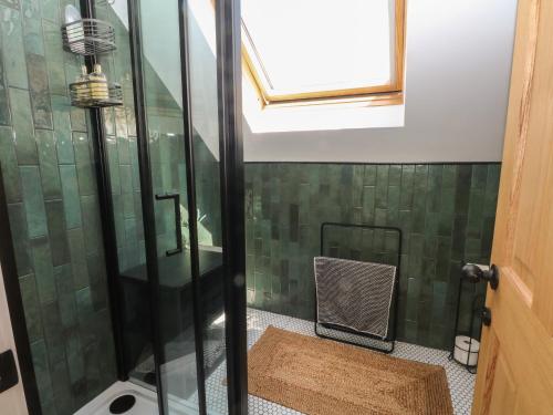 uma casa de banho com um chuveiro e paredes em azulejo verde em Bodlywydd Fawr - Annexe em Ruthin