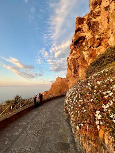 two people standing on a road next to a cliff at Casa Maria - Charme nel cuore del castello in Castelsardo