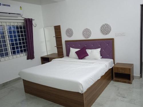 a bedroom with a large bed with a purple headboard at Purple passion in Ranipet