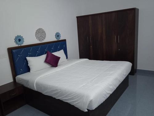 a bedroom with a large bed with a blue headboard at Purple passion in Ranipet