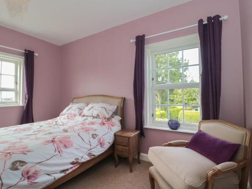 a bedroom with a bed and a chair and a window at Cherry Tree House in Highbridge