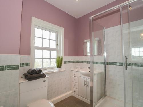 uma casa de banho com paredes cor-de-rosa, um chuveiro e um lavatório. em Cherry Tree House em Highbridge
