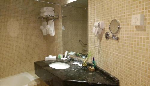 a bathroom with a sink and a mirror and a tub at Aryana Hotel in Sharjah