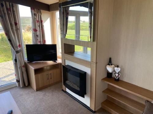 a living room with a fireplace and a television at Mwnt Sea View Caravan with Free WiFi in Cardigan