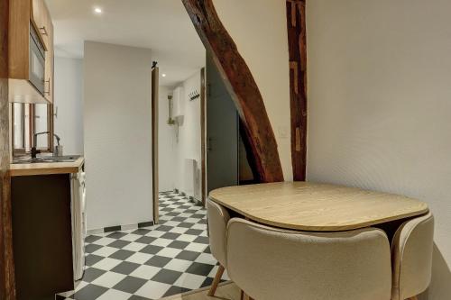 - une cuisine avec une table et un sol en damier dans l'établissement L'Orangerie Versailles, à Versailles