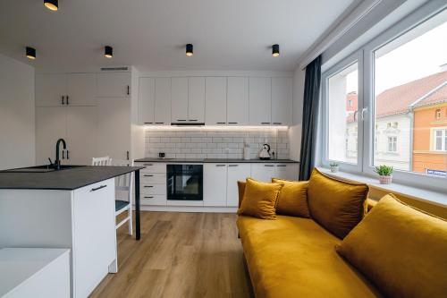 a living room with a yellow couch and a kitchen at Apartament Alpaka 2 in Lidzbark Warmiński
