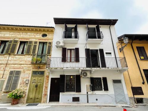 a white building with black doors and balconies at La casetta di Bianca - MonferratoHome in Frassinello Monferrato