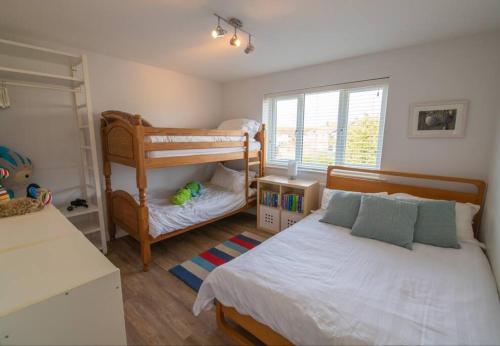 a bedroom with two beds and a bunk bed at Sandy Bottom - 4B op. dunes, Pool Table & Juke Box in Camber