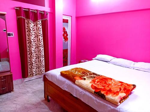 - une chambre aux murs roses et un lit dans une pièce dans l'établissement Rabindra Bilas Homestay, à Bolpur